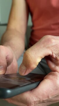Vertical phone scrolling gesture performed by male hand on touchscreen display. Person watching short clip reels or media feeds on modern smart cellular device. Interactive digital