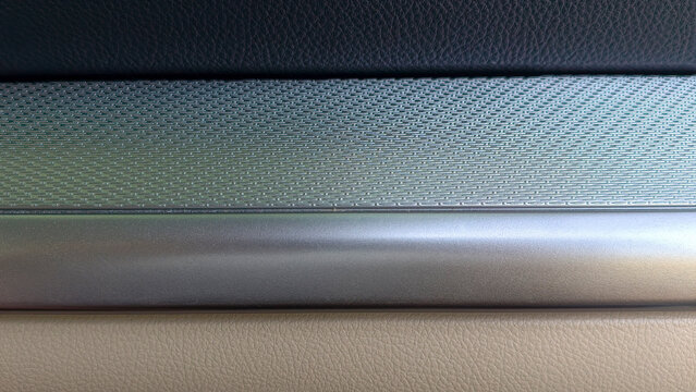 Car interior showing different modern material textures including leather, mesh metallic trim, and brushed metal, creating a contemporary design background