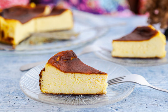 A slice of Basque burnt cheesecake on a glass plate with a fork.