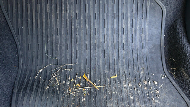 Dirty car rubber floor mat accumulating mud, dust, leaves, and debris, showing a common interior cleanliness challenge and the need for vehicle upkeep