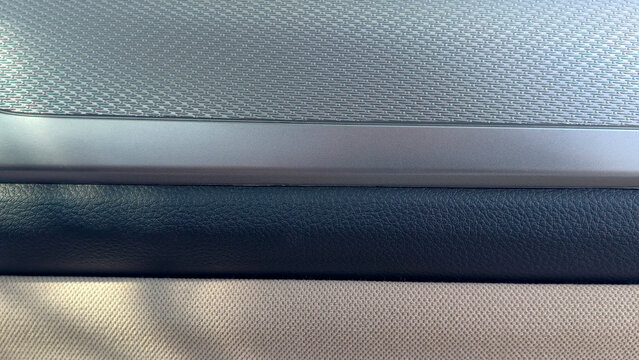 Modern car interior panel blending textured metallic trim, smooth dark blue faux leather and beige woven fabric, highlighting sleek automotive design and material contrast
