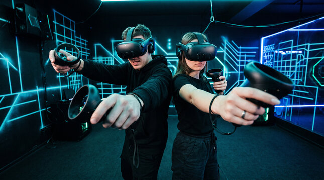 Young man and woman wearing virtual reality headsets and holding motion controllers while playing an immersive VR game together, virtual reality gaming, VR technology, metaverse, interactive entertain