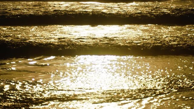 Golden sunset over the Atlantic Ocean coastline. Shimmering calm sea water waves washing the sandy shore. Serene evening beach landscape, relaxation and travel concept.