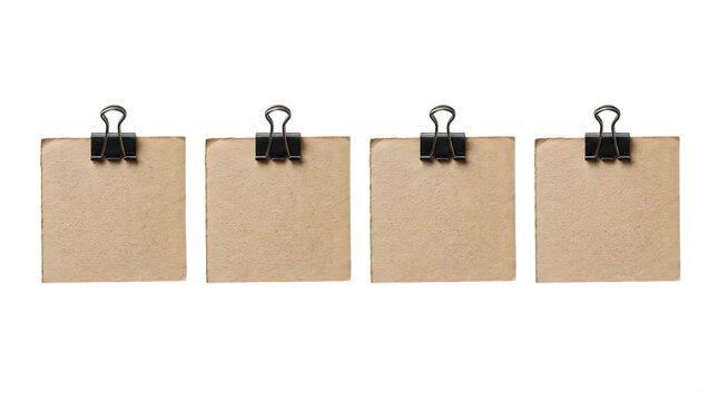 Four square pieces of brown paper with black metal binder clips for notes and office organization