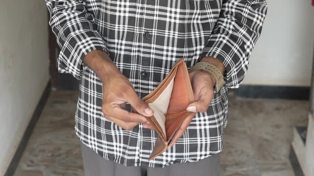 Man holding an empty leather wallet showing poverty indoors