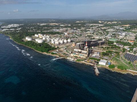 Aerial view of the industrial complex with large storage tanks and power plant facilities along the coastline in Bajos de Haina, San Cristobal Province, Dominican Republic.