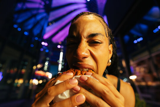 Woman Biting Into Burger at Night