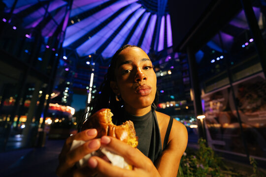 Woman Eating Burger at Night