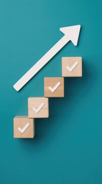 Four wooden blocks with checkmarks arranged as steps, with a white upward arrow indicating progress and achievement on a teal background.