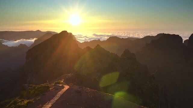 Stunning time lapse of a vibrant golden sunset above the clouds at Pico do Arieiro mountain peak in Madeira, Portugal. 