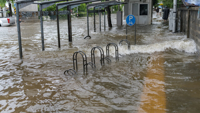 Severe urban flooding submerging a bicycle parking area on a city street after heavy rainfall