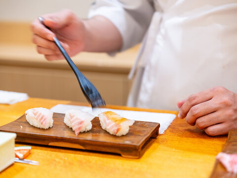 Sushi Chef Brushing Nikiri Sauce on Akami Tuna Nigiri Wooden Plate Chef Brushing Akami Nigiri Tongs