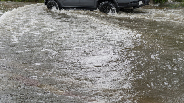 A gray pickup truck driving through a flooded street during a heavy rainstorm in the city