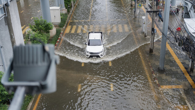 A white pickup truck driving through a flooded city street during a heavy rainstorm event