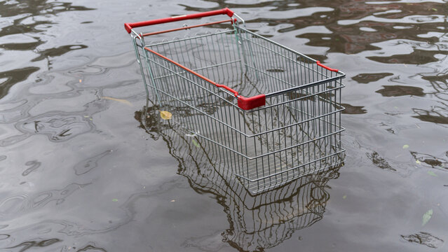 An abandoned metal shopping cart submerged in dark murky water after a heavy rainstorm event
