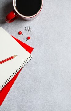 Workplace with notebook, pencil, and red cup of coffee, top vertical view 