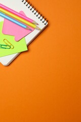 Notebook and school stationery on orange background, top vertical view. © Sunlight
