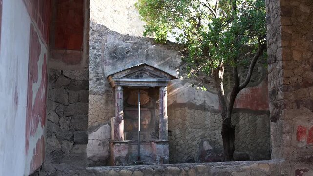ERCOLANO, ITALY - SEPTEMBER 2026: Ancient Roman shrine lararium inside the courtyard of the House of the Carbonized Furniture in Herculaneum archaeological site.