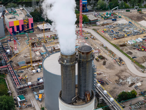 Aerial view of Heizkraftwerk Reuter West power plant with steam rising from chimneys, surrounded by industrial infrastructure, construction cranes, and pipes in Berlin, Berlin, Germany.