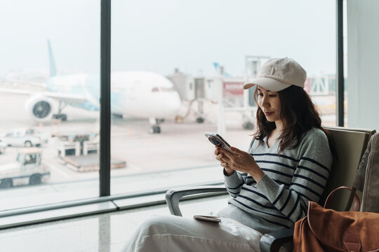 Female tourist using mobile phone while waiting for her flight at the gate