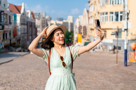 Happy young Asian woman tourist taking selfies and enjoying travel photography and city exploration