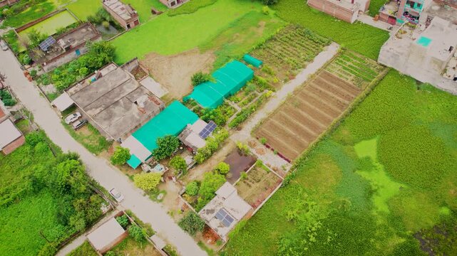 Aerial view of solar scheme installation with greenhouses and agricultural plots in Lucknow, Uttar Pradesh, India.