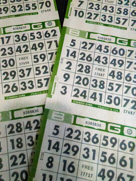 Close up of multiple bingo cards with numbered grids for a traditional game of chance and luck
