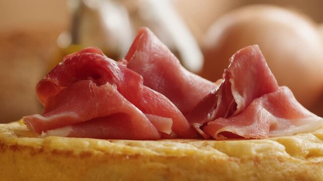 Spanish omelette with jamon serrano, tortilla and iberico cured ham appetizer on wooden table, traditional Spanish breakfast close up in cafe
