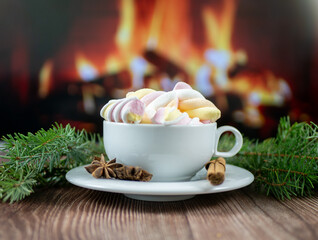 Festive Christmas card design with marshmallow hot drink in ceramic cup, pine twigs, and warm fireplace bokeh for winter greetings © Oksana