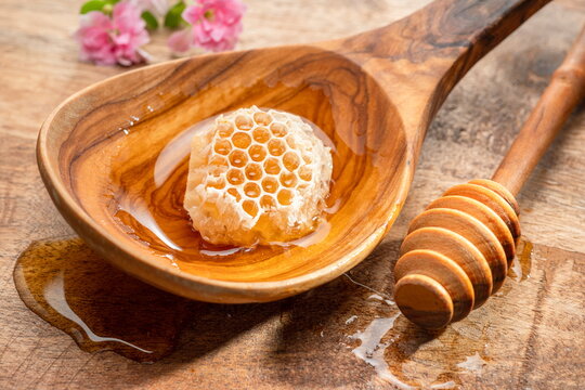  Dark golden amber honey in a clear glass jar on a wooden spoon