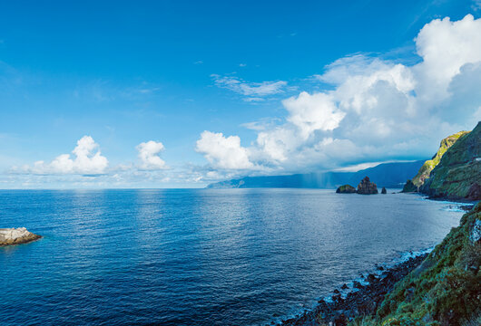 Dramatic landscape view of the northern coast of Madeira with heavy clouds gathered over the sea and volcanic rocks at Ribeira da Janela.