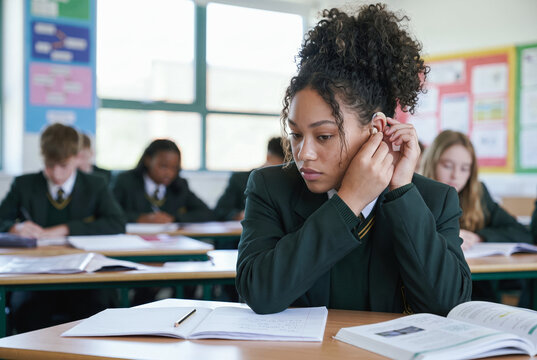 Student adjusting a hearing aid in a classroom
