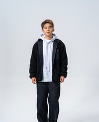 A young Asian man is wearing a black Sherpa fleece jacket, with a light gray hooded sweater underneath. © jeson