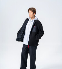 A young Asian man is wearing a black Sherpa fleece jacket, with a light gray hooded sweater underneath. © jeson