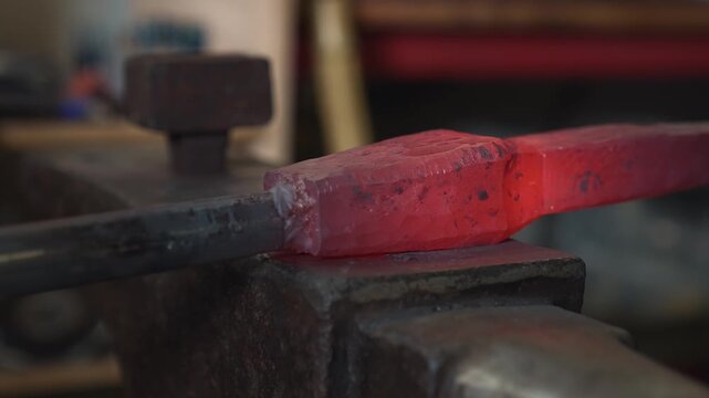 A blacksmith in the workshop takes out a red-hot spearhead (or sword blade) and hammers it while the heat lasts.