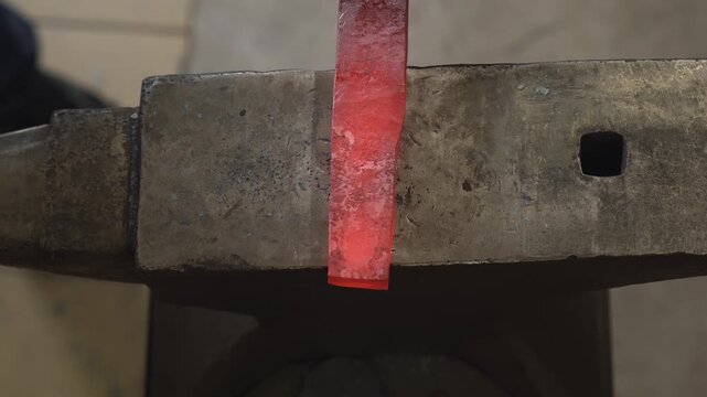 A blacksmith in the workshop takes out a red-hot spearhead (or sword blade) and hammers it while the heat lasts.