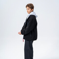 A young Asian man is wearing a black Sherpa fleece jacket, with a light gray hooded sweater underneath. © jeson