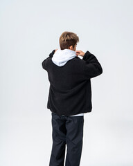 A young Asian man is wearing a black Sherpa fleece jacket, with a light gray hooded sweater underneath. © jeson