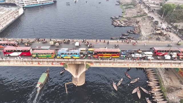 Aerial view of Sadarghat bridge with buses crossing over the Buriganga River filled with numerous wooden boats in Dhaka, Dhaka Division, Bangladesh.