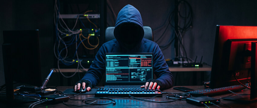 hacker theif robbery and terrorist man in hoodie is hacking coding an computer laptop to attack data server network system online in technology internet security concept, y2k scifi cyberpunk theme