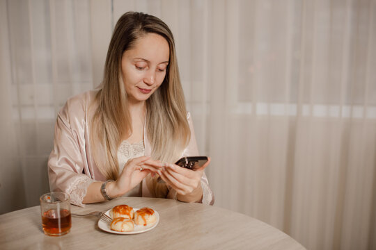 woman using smartphones, drinking tea and having meal at home