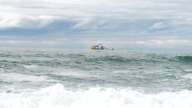 Footage of fishing boat fishing in wavy sea.