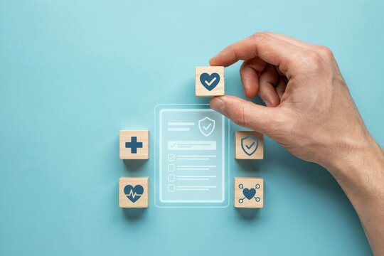 Hand placing a wooden block with a heart checkmark icon near a health insurance form