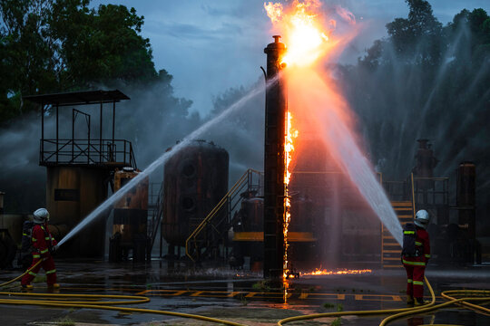 Industrial fire response team battles intense flames and smoke with fire hoses, representing firefighting operations, workplace safety, emergency rescue, and hazard control.