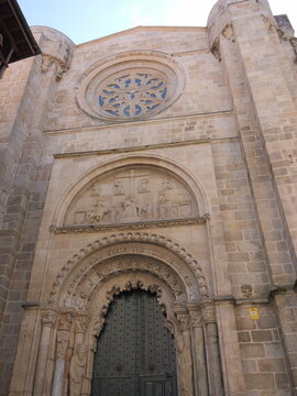 View of the Romanesque facade of the Catedral de Ourense featuring a detailed rose window and an ornate arched doorway with stone carvings in Ourense, Ourense, Spain.