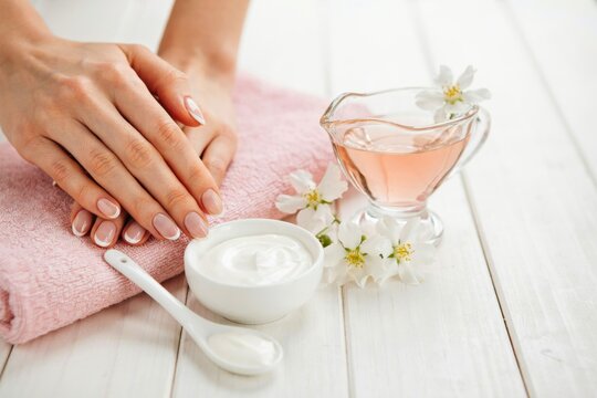 Woman hands with manicure and spa treatment with cream and flowers