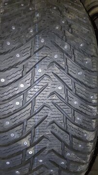 Close-up of studded winter tire tread with metal traction studs
