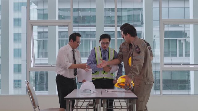Construction worker engineer safety meeting with hard hat inside office building, industrial worker colleague teamwork and project coordination discussion, reflective vest, documents, business