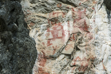 Ancient Red Rock Paintings of Human Figures on a Textured Cliff Face © VuVan