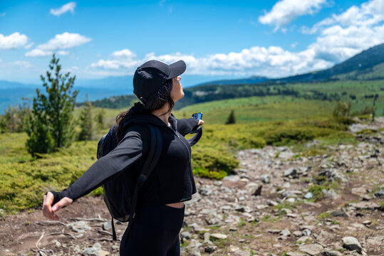 Relaxed woman standing in the summer mountain with open arms